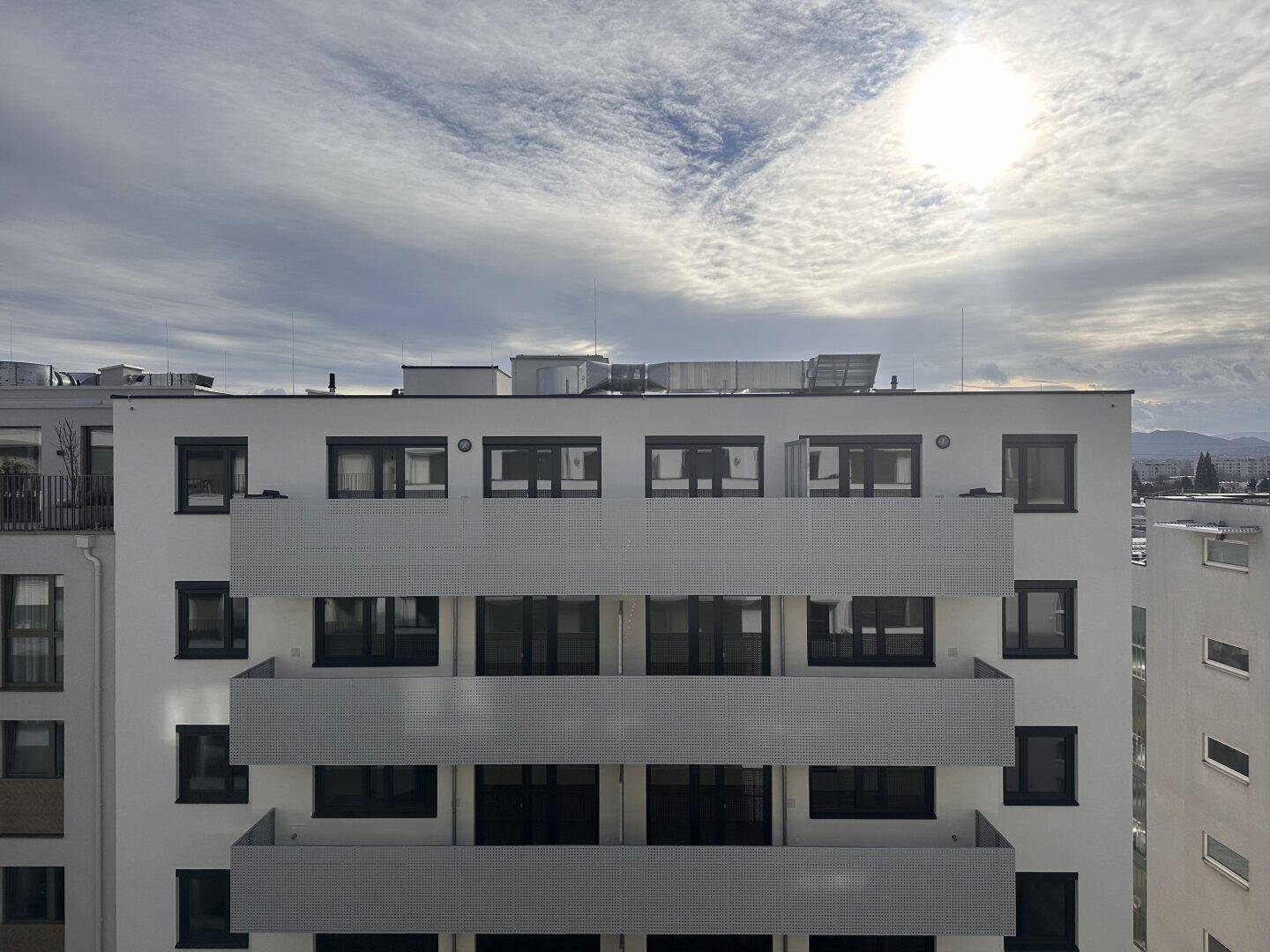 Balkon eines modernen Wohngebäudes mit Blick auf den Himmel und die umliegende Bebauung.