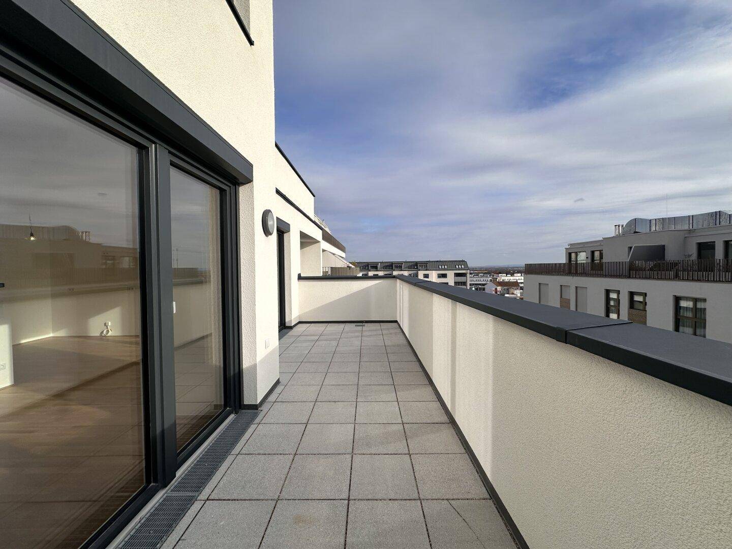 Geräumige Dachterrasse mit Fliesenboden und weitem Blick über die Stadt.
