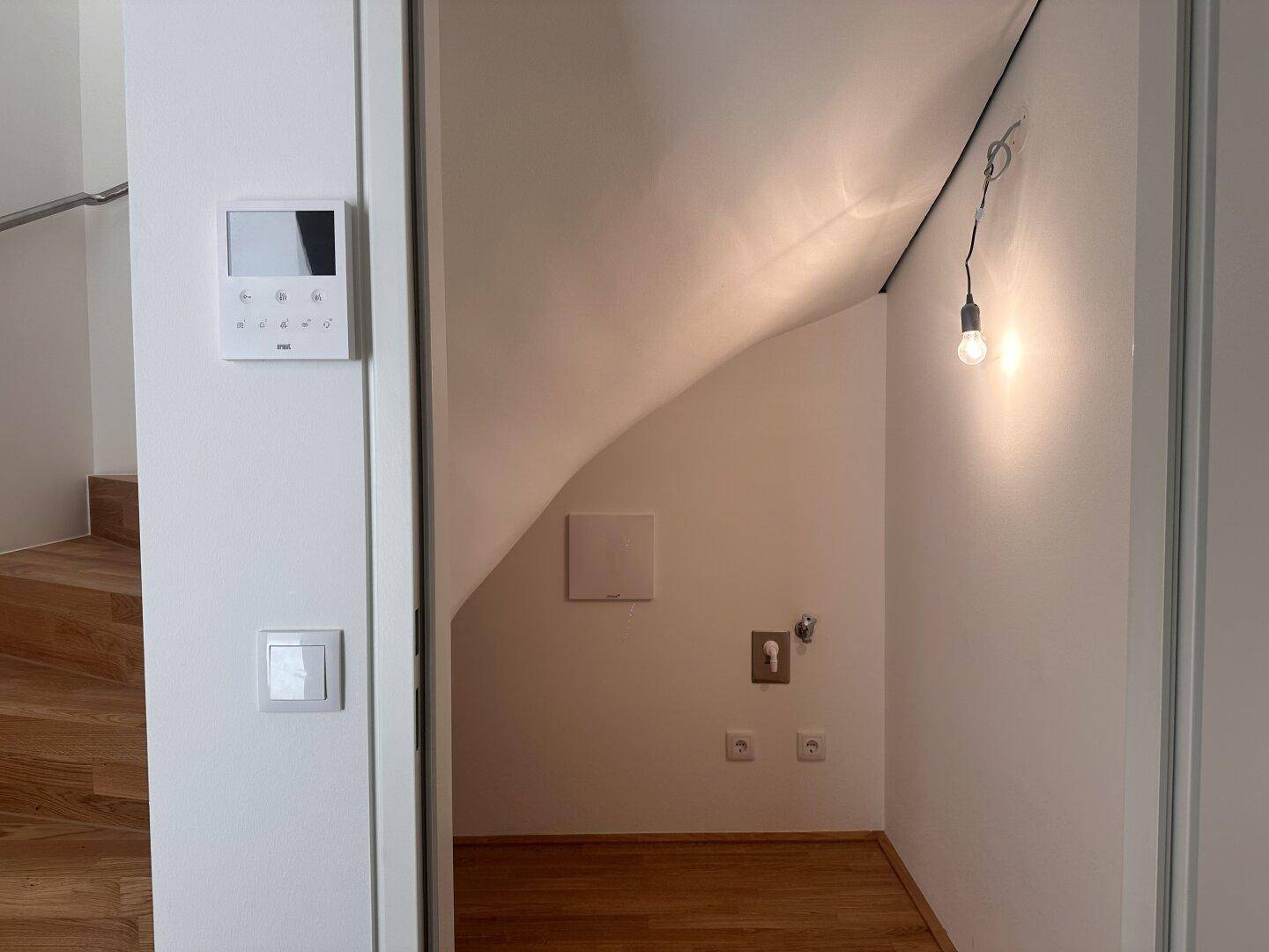 Kleiner Abstellraum unter der Treppe mit Dachschräge und Beleuchtung.