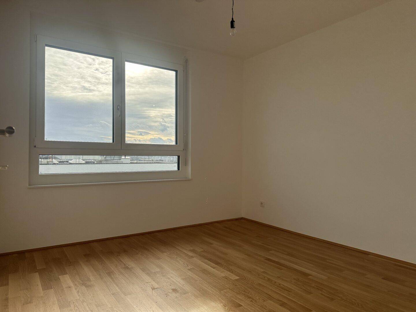 Geräumiges Schlafzimmer mit Parkettboden und Fenster, das einen weiten Blick ermöglicht.