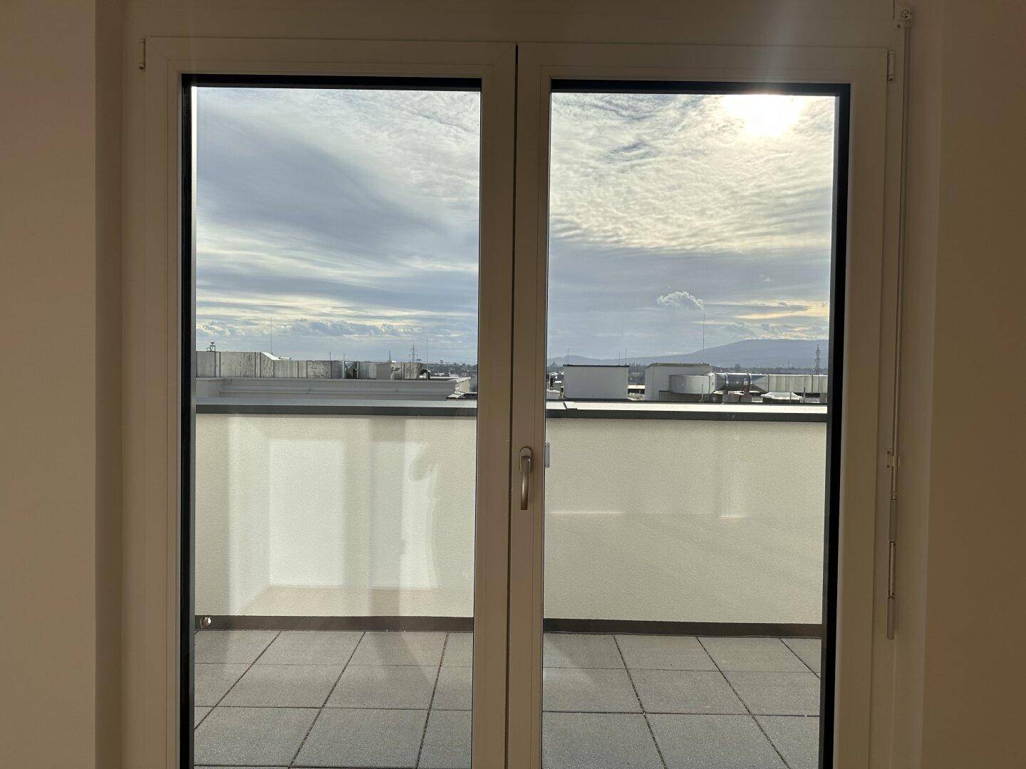 Langer Balkon mit Fliesenboden und Blick auf die umliegende Stadtlandschaft.
