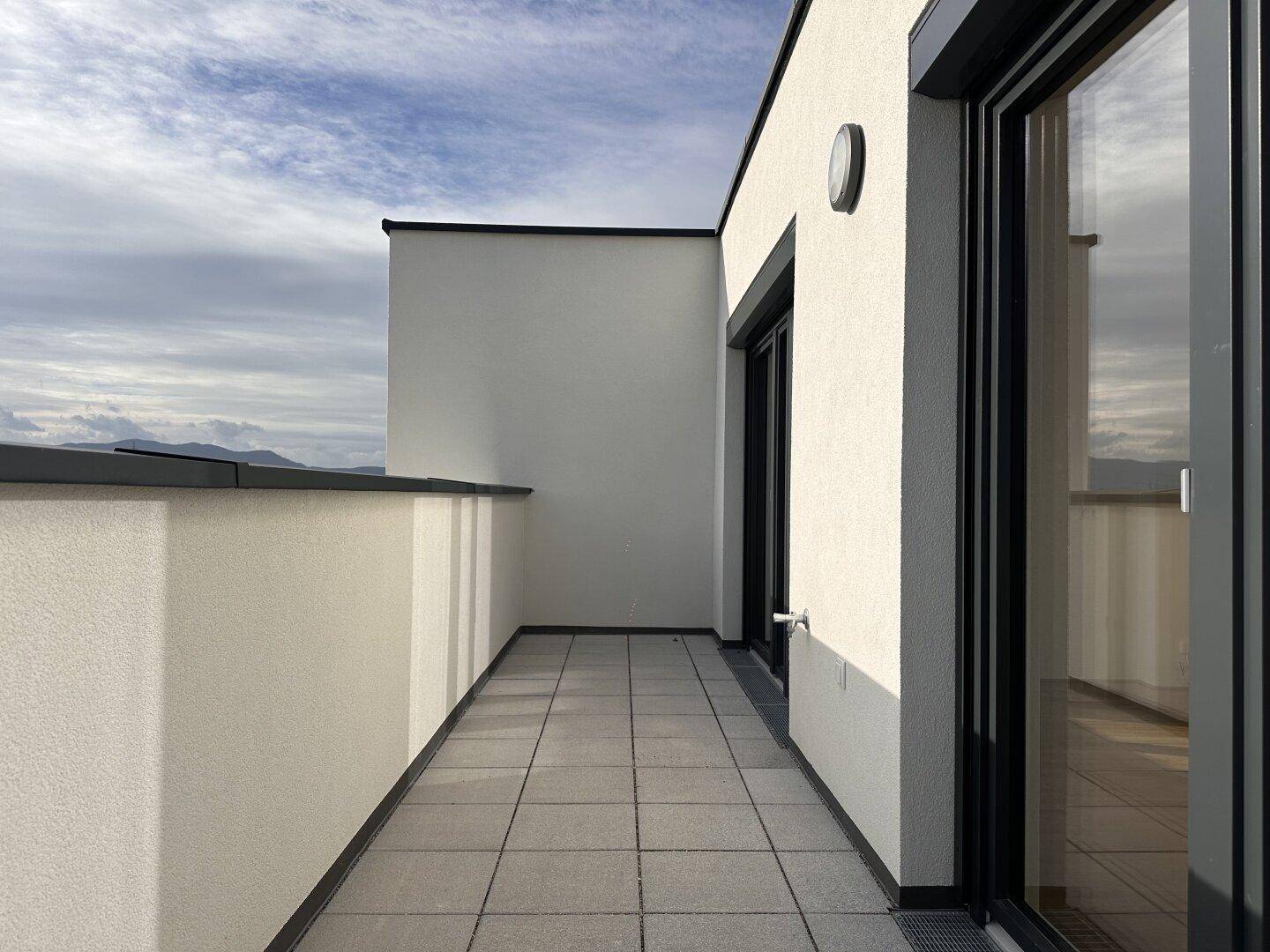 Geräumiger Balkon mit Fliesenboden und weitem Blick über die Stadt und die Berge.