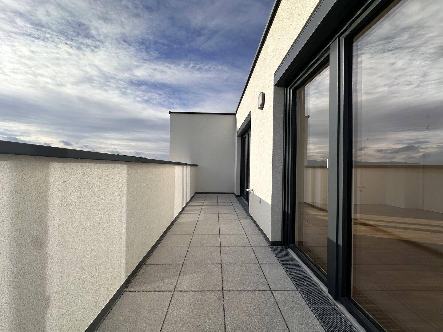 Breiter Balkon mit Fliesenboden und Panoramablick über die Stadt und die umliegende Landschaft.