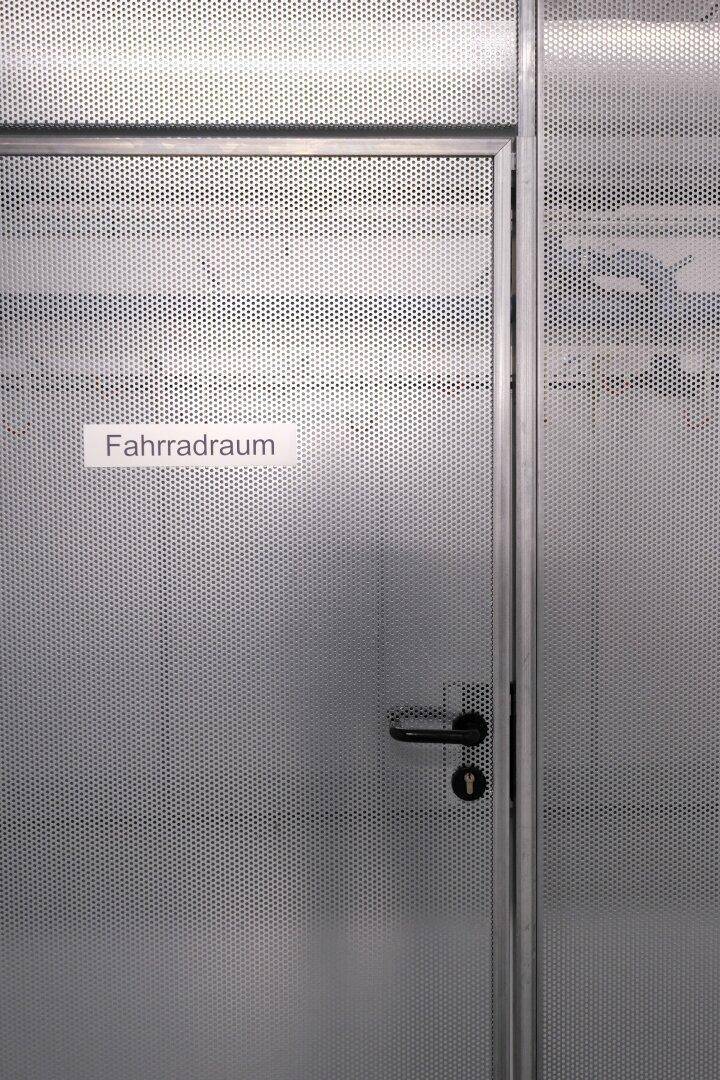 Eingang zum Fahrradraum mit perforierter Metalltür und modernem Design.