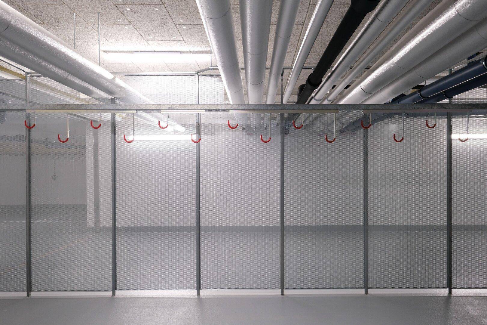Abgetrennte Lagerbereiche mit Metallgittern und sichtbaren Rohren an der Decke.
