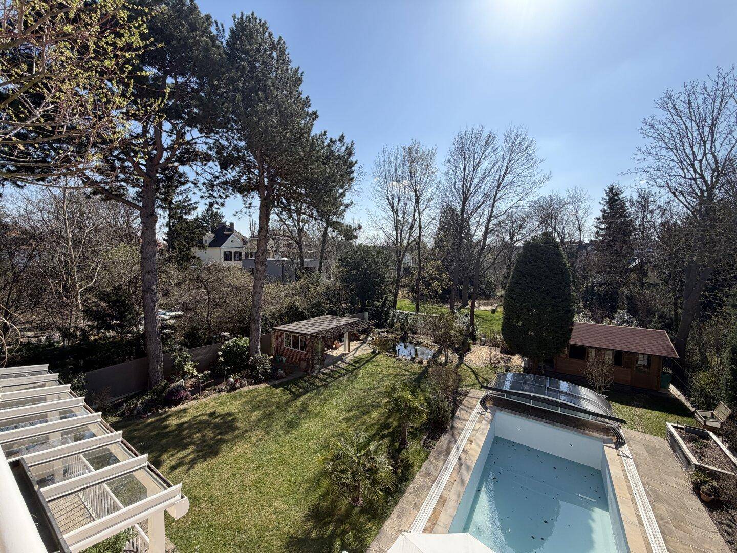 Weitläufiger Garten mit großem Pool, altem Baumbestand und einem Gartenhaus.
