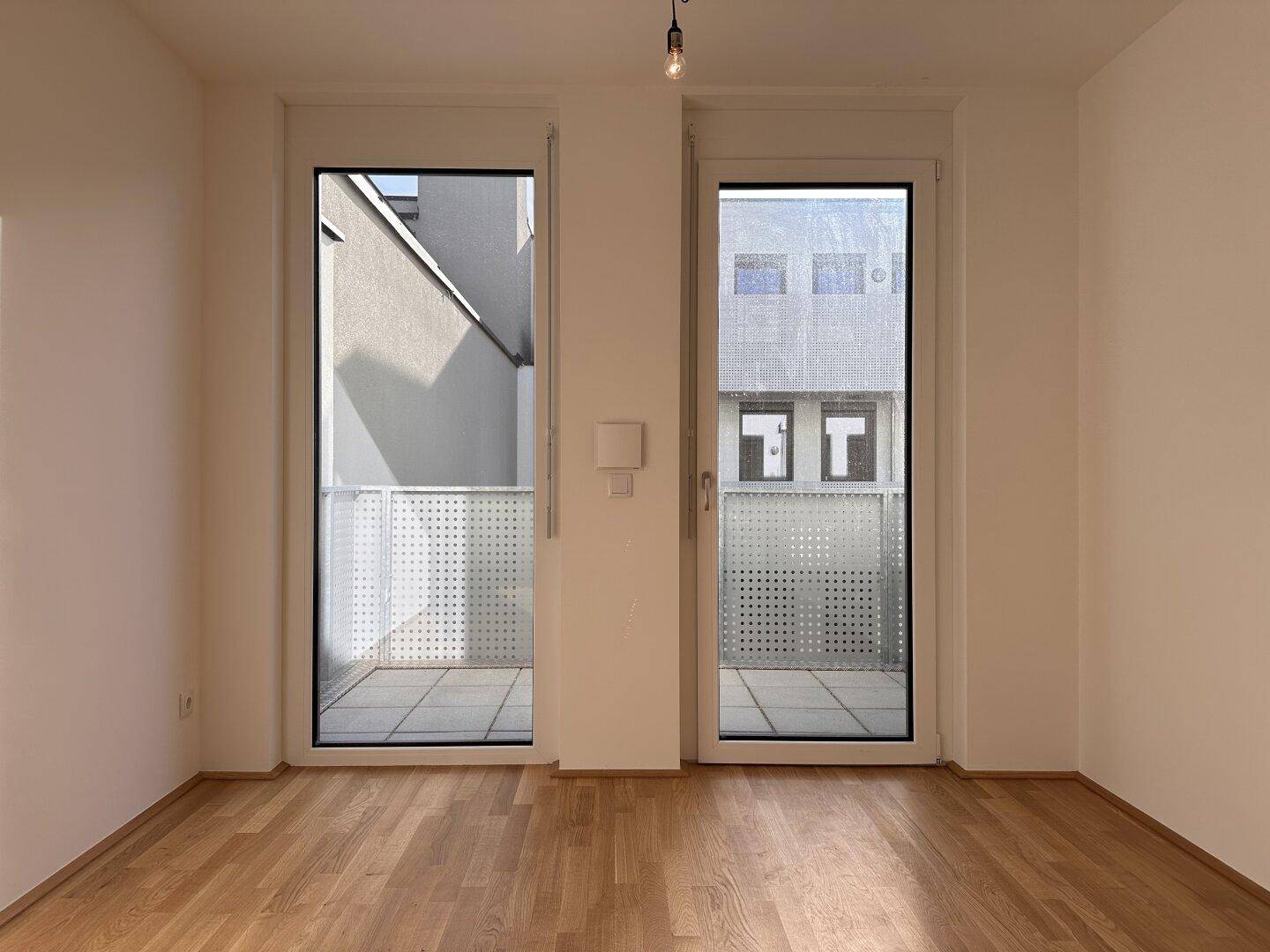 Geräumiges Zimmer mit großen Fenstern und Balkonzugang, bietet viel Tageslicht und Ausblick.