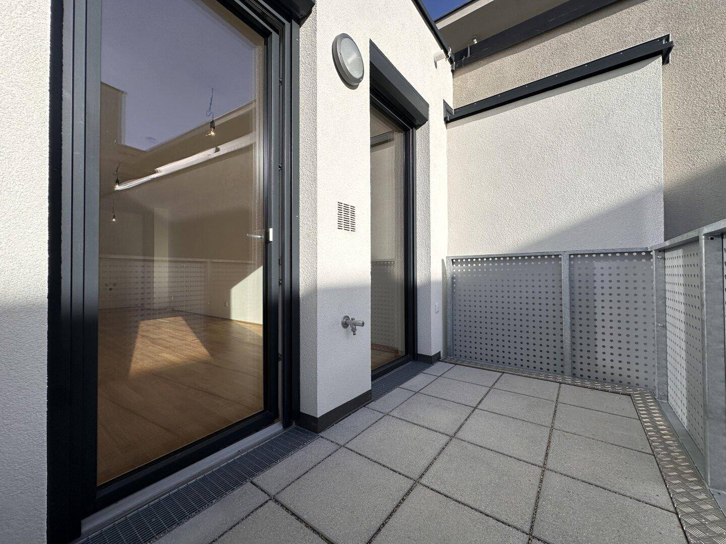 Heller Balkon mit Fliesenboden und Metallgeländer, bietet einen angenehmen Außenbereich.