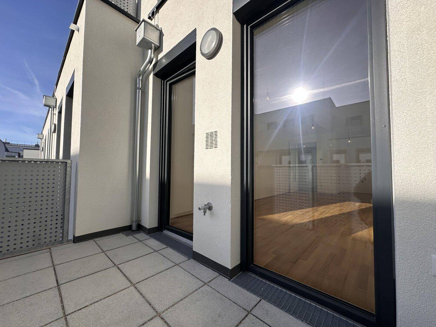 Sonniger Balkon mit Fliesenboden und Blick auf die Umgebung, ideal zum Entspannen.