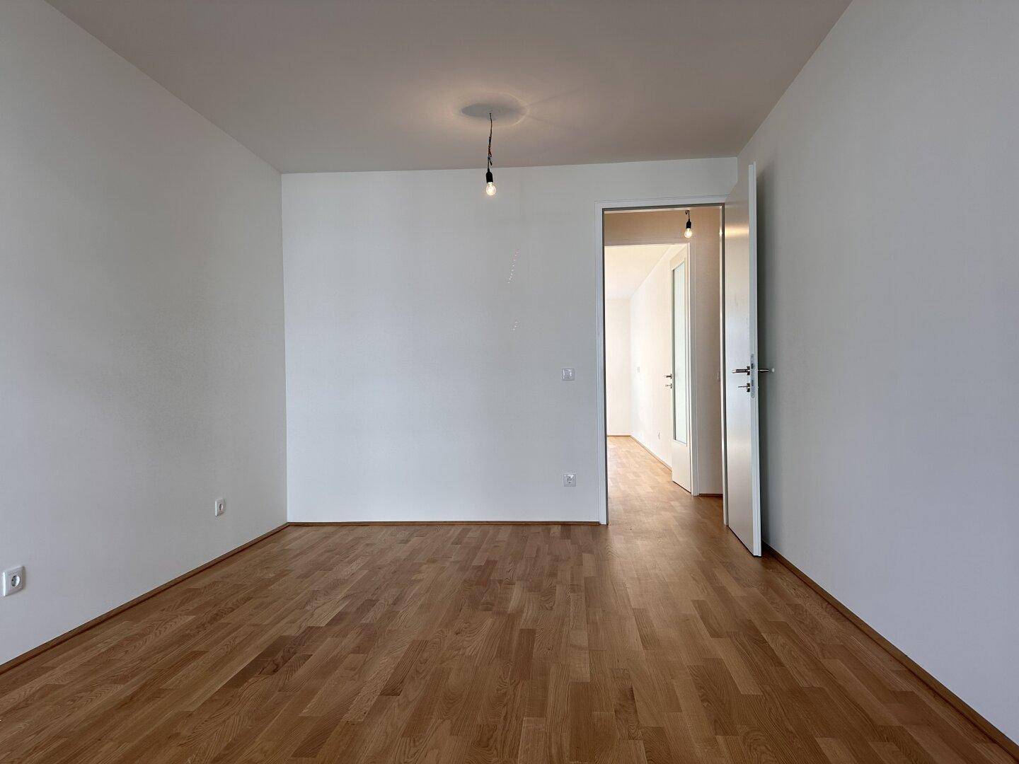 Leeres, helles Zimmer mit Parkettboden und weiß gestrichenen Wänden, ideal für individuelle Einrichtung.