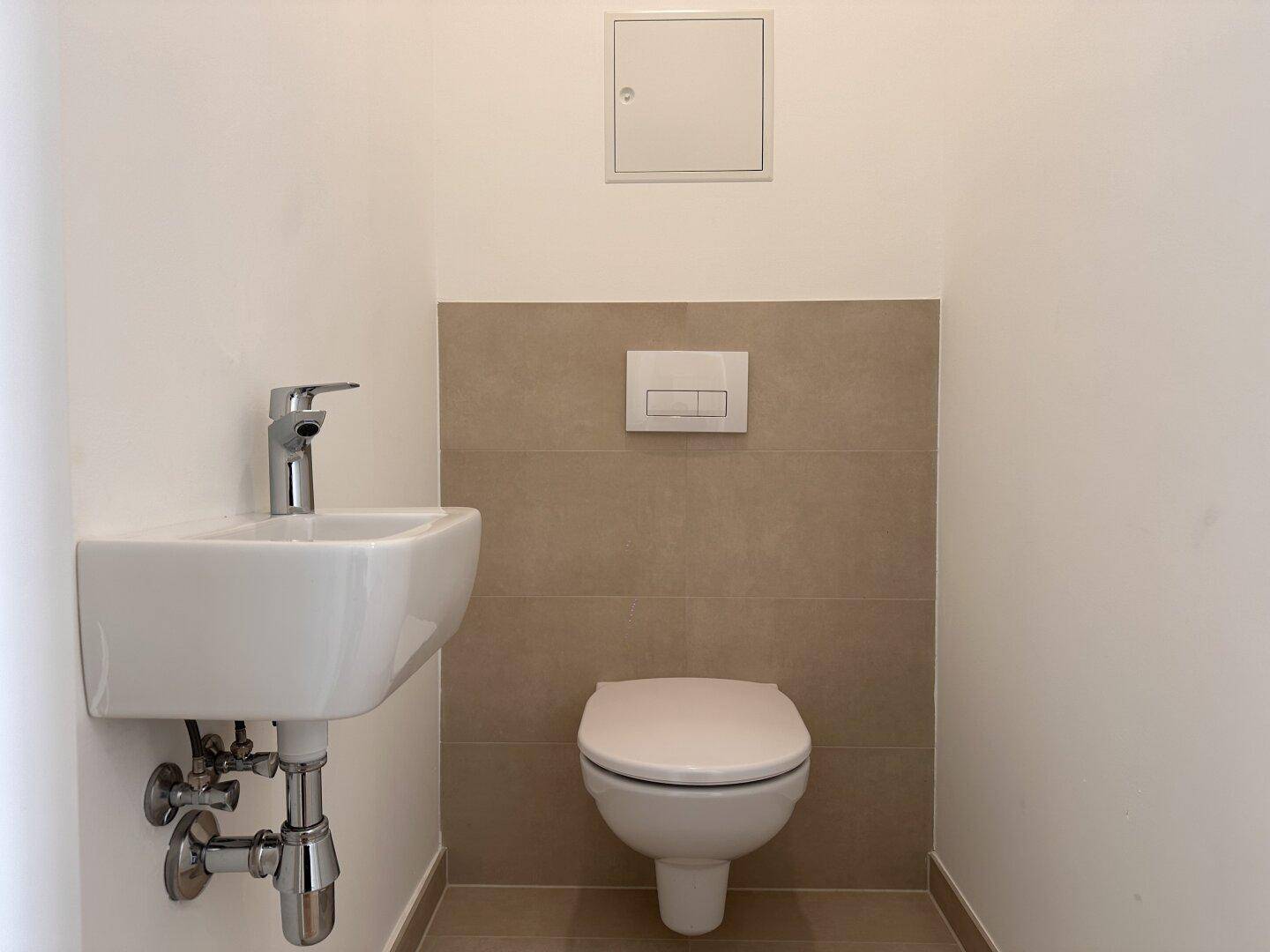 Modernes Gäste-WC mit wandhängender Toilette und kleinem Waschbecken.