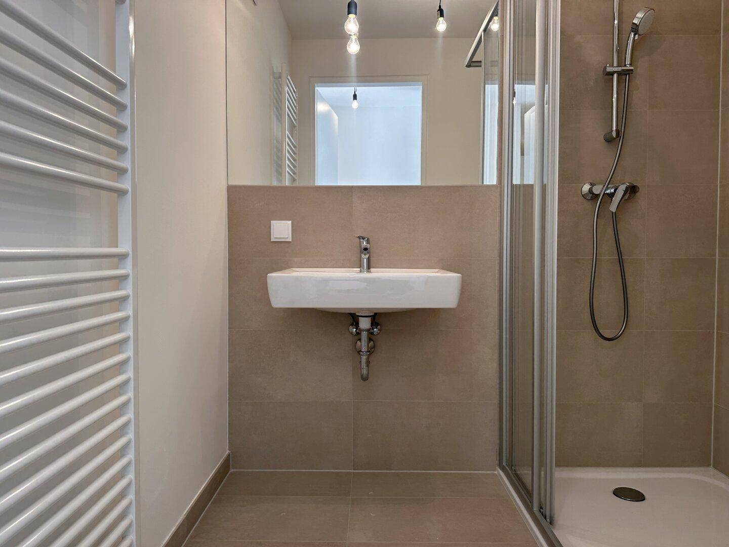Modernes Badezimmer mit Dusche, Waschbecken und beheiztem Handtuchhalter.