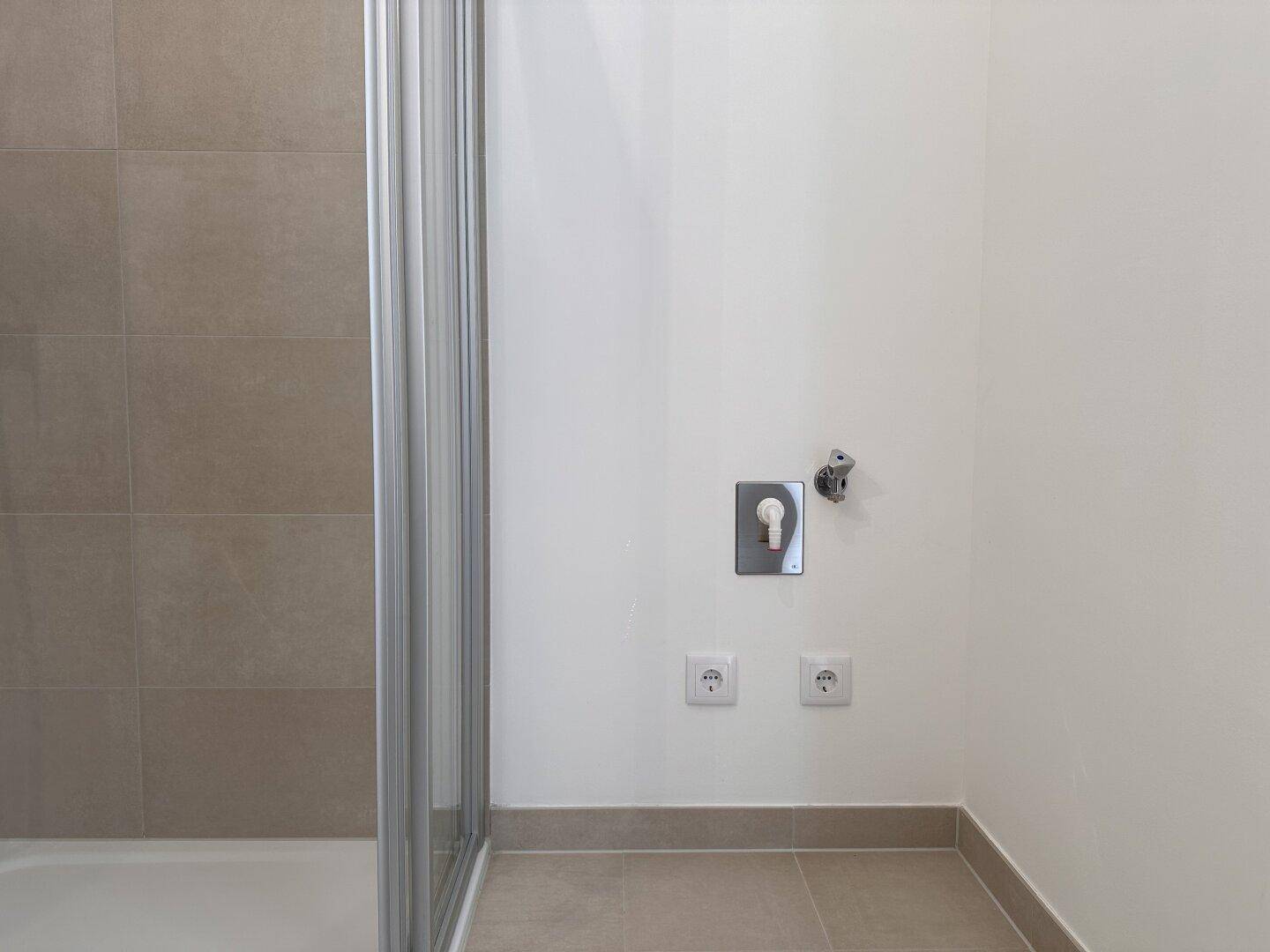 Bereich im Badezimmer mit Anschlussmöglichkeiten für eine Waschmaschine.