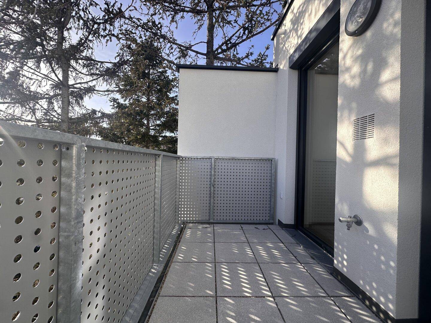 Sonniger Balkon mit Blick auf Bäume und die Umgebung, ausgestattet mit modernem Geländer.