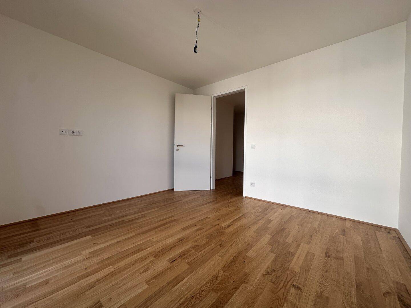 Leerer Raum mit Holzboden und weiß gestrichenen Wänden, ideal für individuelle Gestaltung.