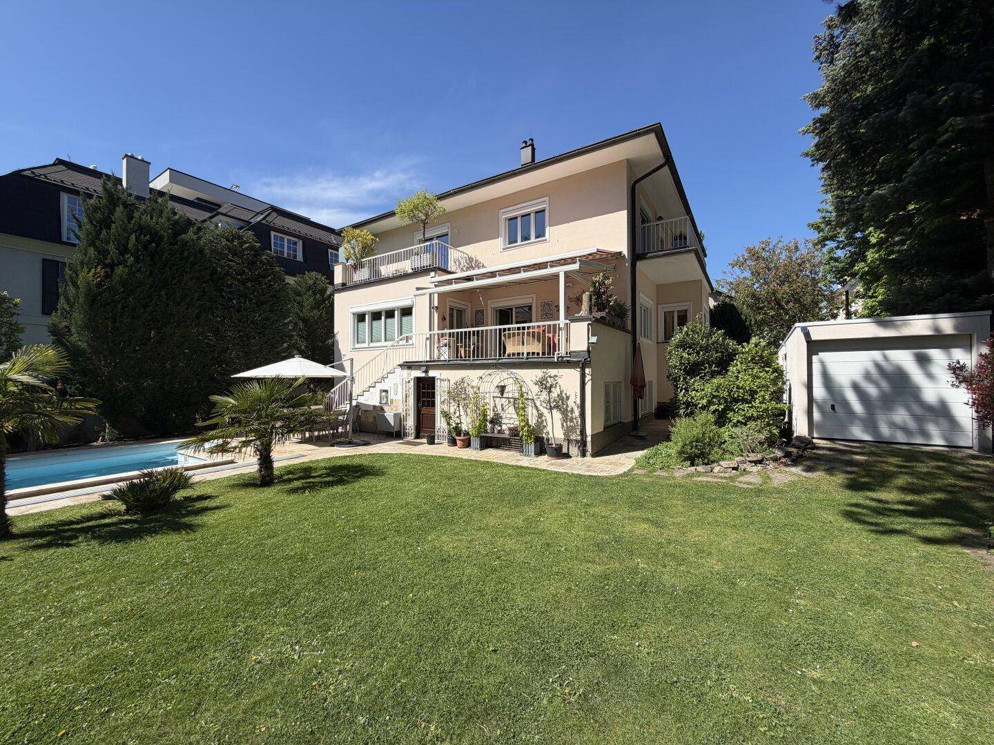 Gepflegter Garten mit Rasen, Swimmingpool und einem freistehenden Garagengebäude neben dem Haus.