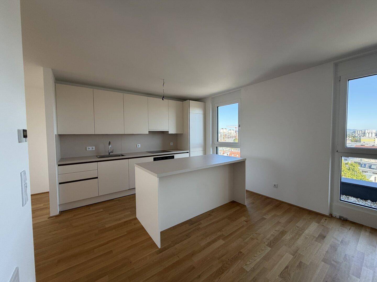Helle, moderne Einbauküche mit Kücheninsel und großen Fenstern, die viel Tageslicht hereinlassen.