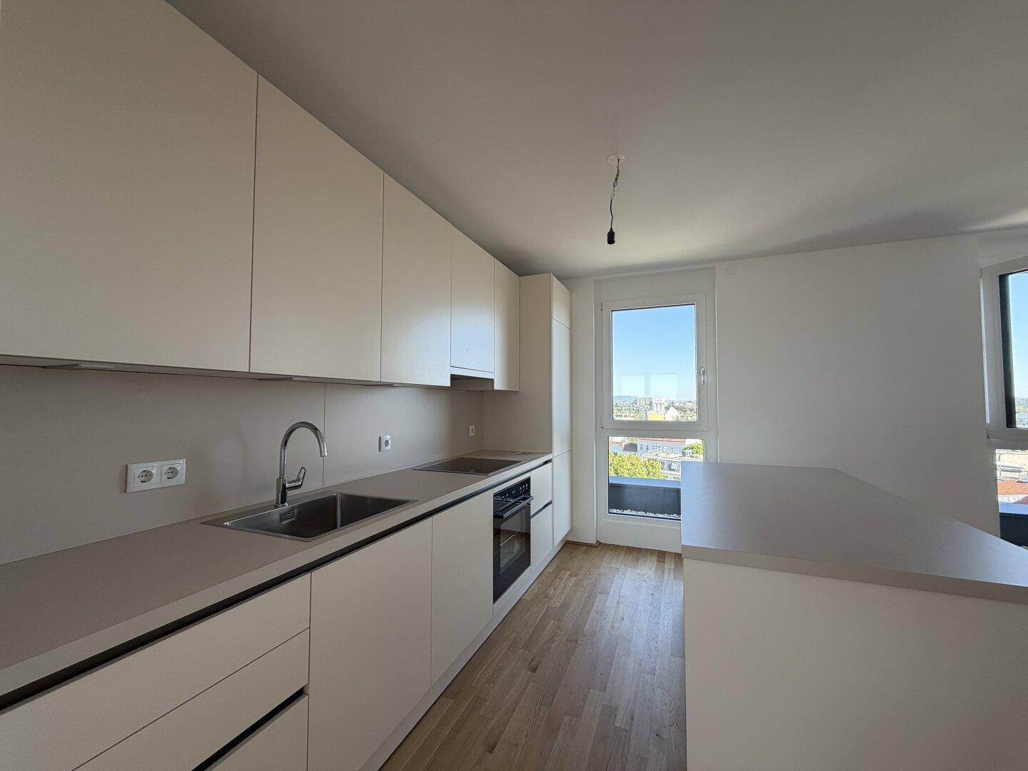 Moderne Küche mit hellen Fronten und Arbeitsplatten, ausgestattet mit Spüle und Kochfeld.