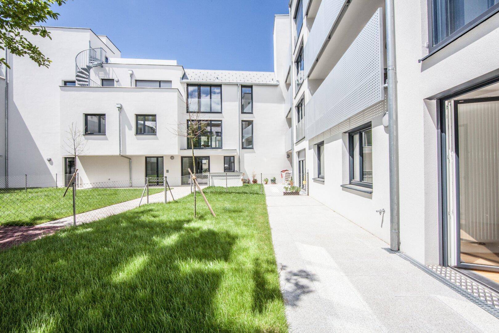 Weitläufiger Innenhof mit Rasenflächen und modernen Wohngebäuden, die einen ruhigen Blick bieten.