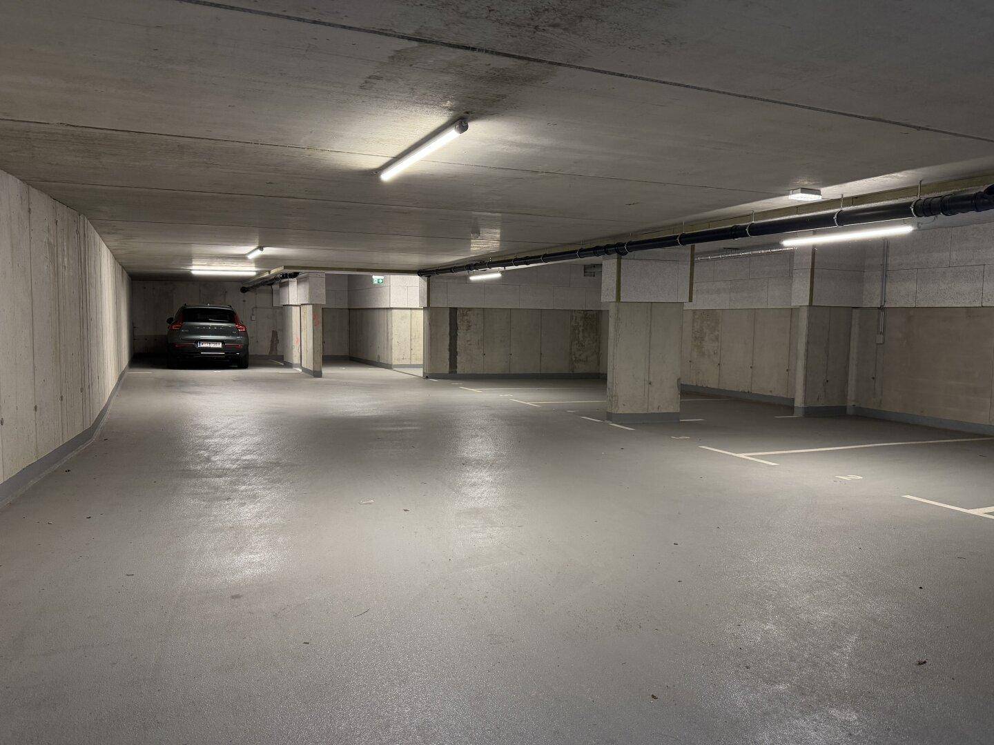 Geräumige Tiefgarage mit Betonwänden und ausreichend Parkplätzen für Fahrzeuge.