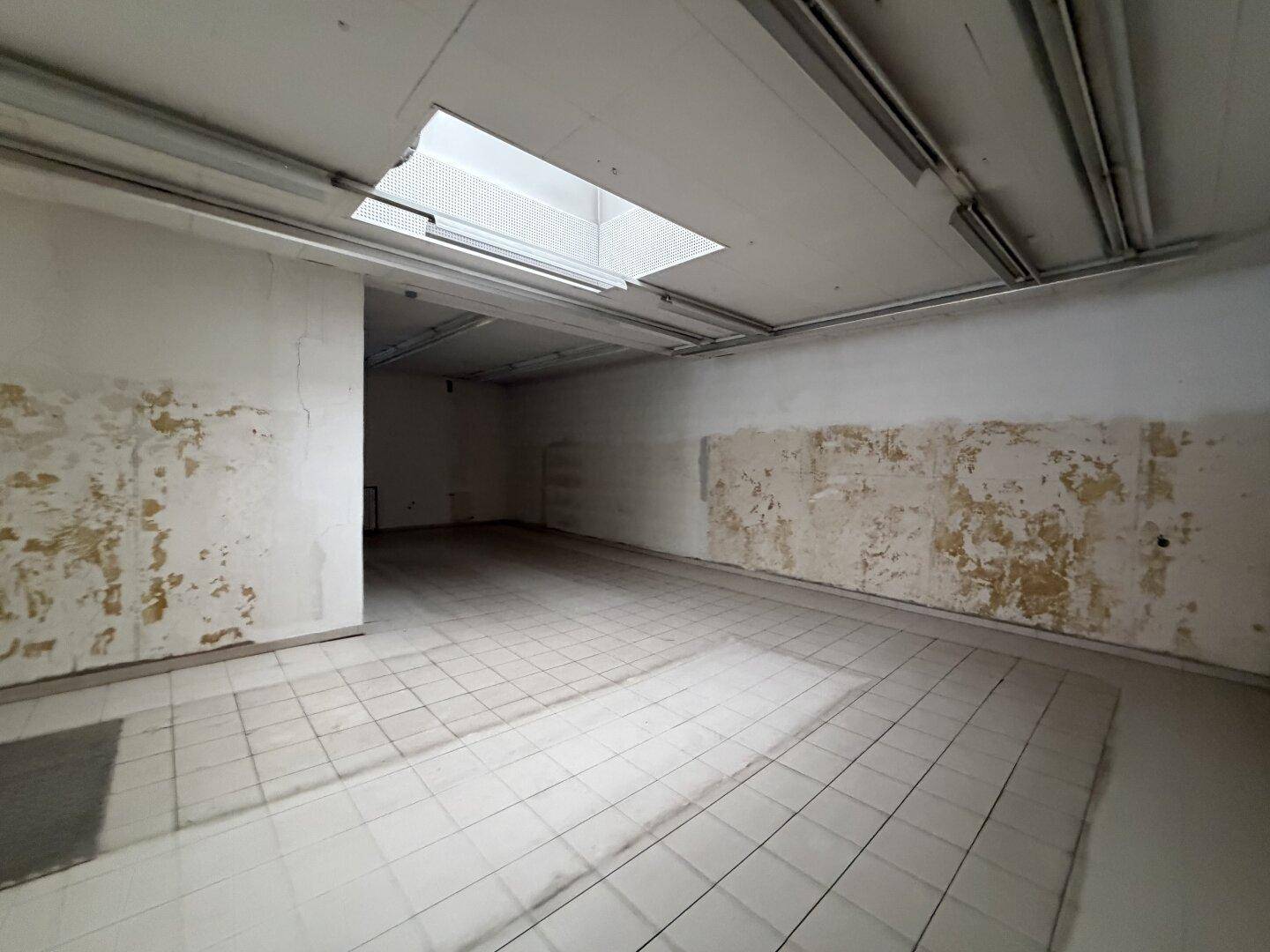 Hinterer Teil des Geschäftsraums mit Fliesenboden und einem Oberlicht, das Tageslicht hereinlässt.