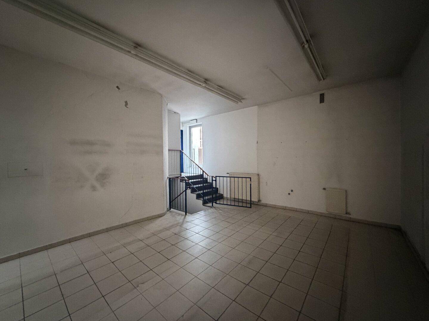Treppenaufgang im hinteren Teil des Geschäftsraums mit Metallgeländer und Fliesenboden.