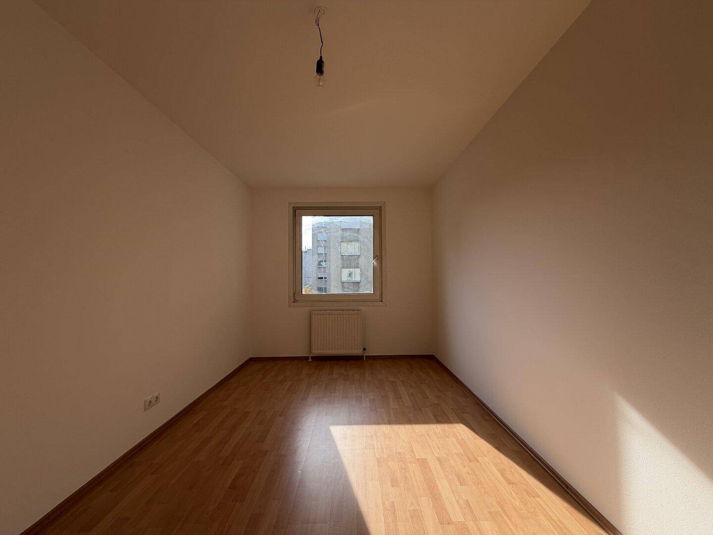Ruhiges Zimmer mit Laminatboden und Fenster, das sich gut als Schlaf- oder Arbeitszimmer eignet.