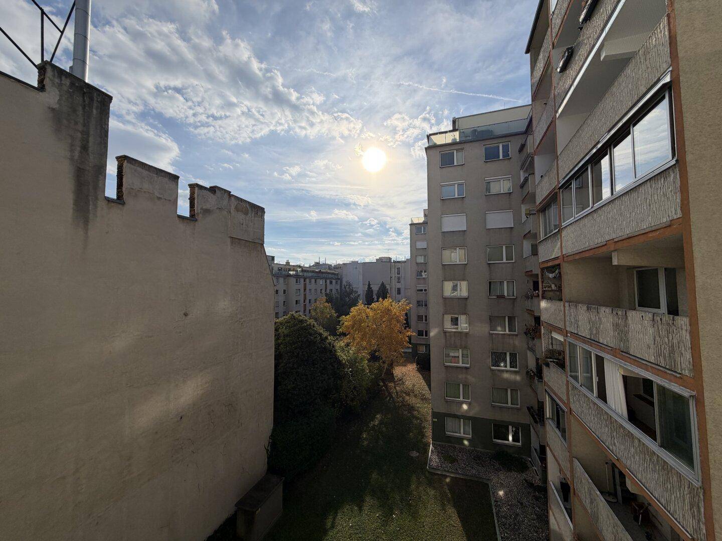 Weitblick über die Stadt mit Wohngebäuden und Bäumen unter einem strahlend blauen Himmel.