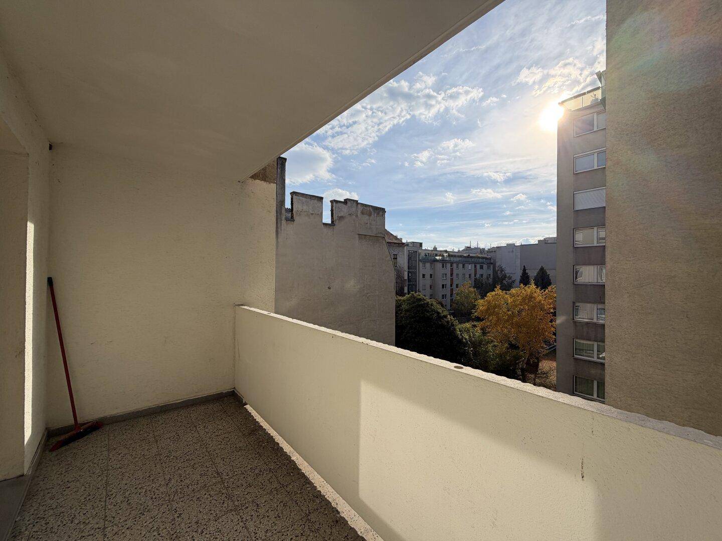 Sonniger Balkon mit Fliesenboden und Blick auf die umliegenden Gebäude und Grünflächen.