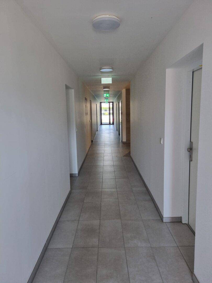 Langer, heller Flur mit Fliesenboden und Türen zu den einzelnen Wohneinheiten.