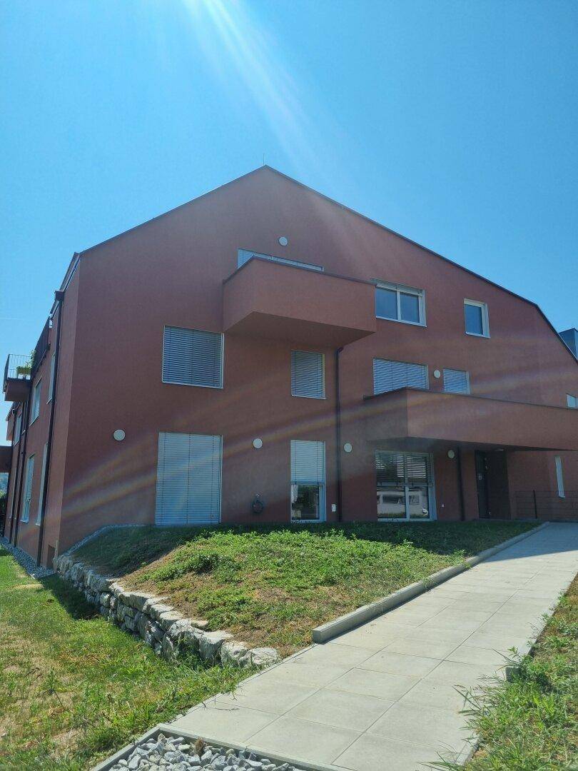 Vorderansicht des modernen Wohngebäudes mit roter Fassade und gepflegtem Außenbereich.