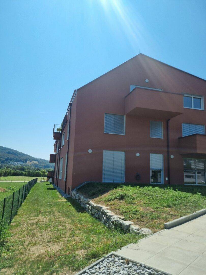 Seitenansicht des Wohngebäudes mit roter Fassade und sonnigem Außenbereich.