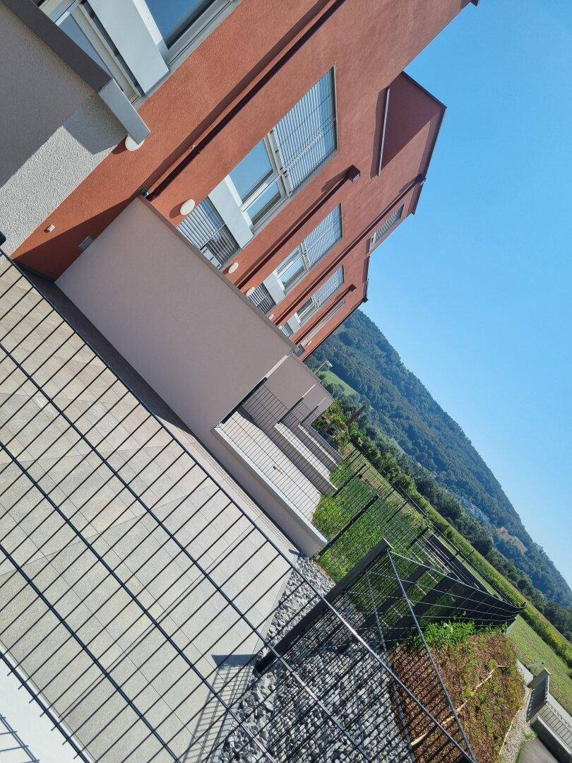Terrasse mit Fliesenboden und Blick auf die umliegende grüne Landschaft und Berge.