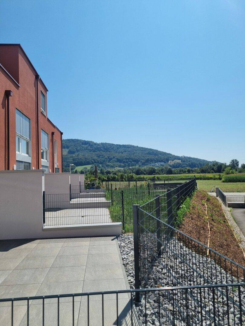 Geräumige Terrasse mit Fliesenboden und weitem Blick auf die grüne Landschaft.