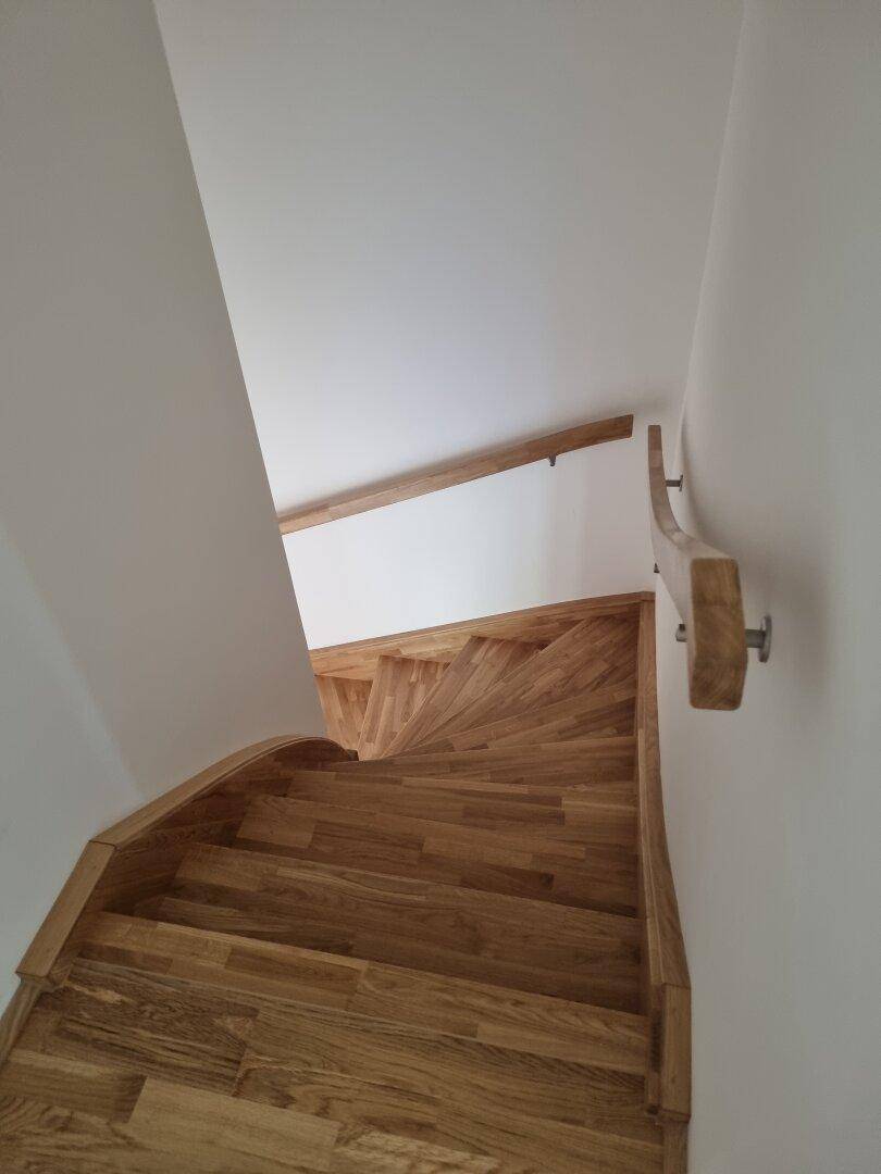 Elegante Holztreppe mit geschwungenem Handlauf, die zu den oberen Etagen führt.