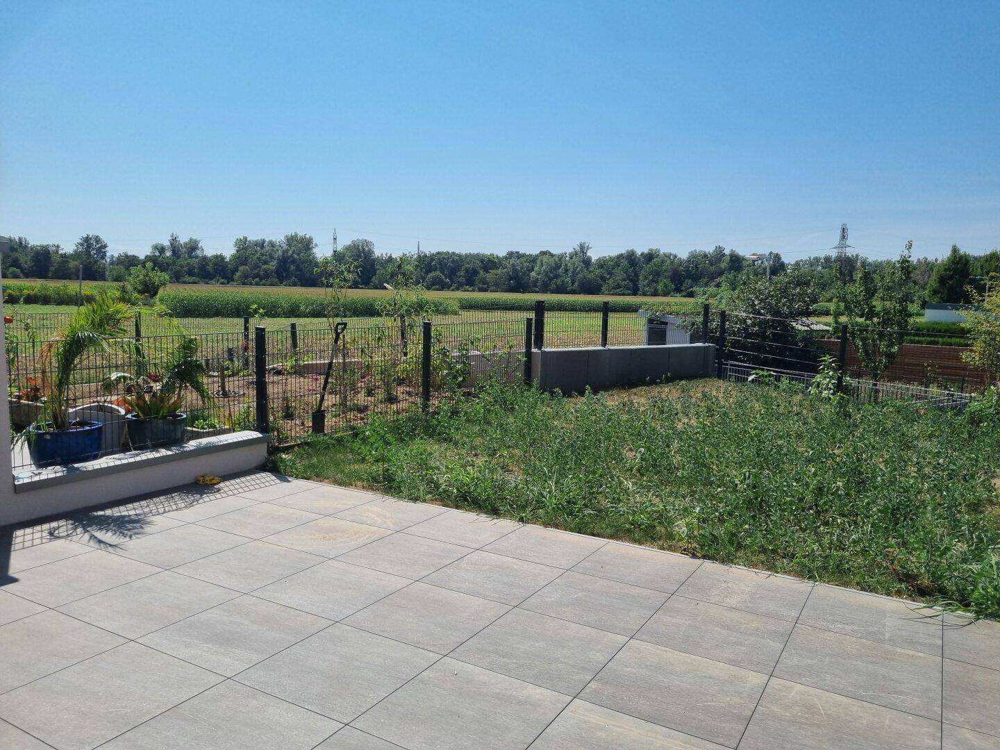 Private Terrasse mit angrenzendem Gartenbereich und Blick auf die umliegende Natur.