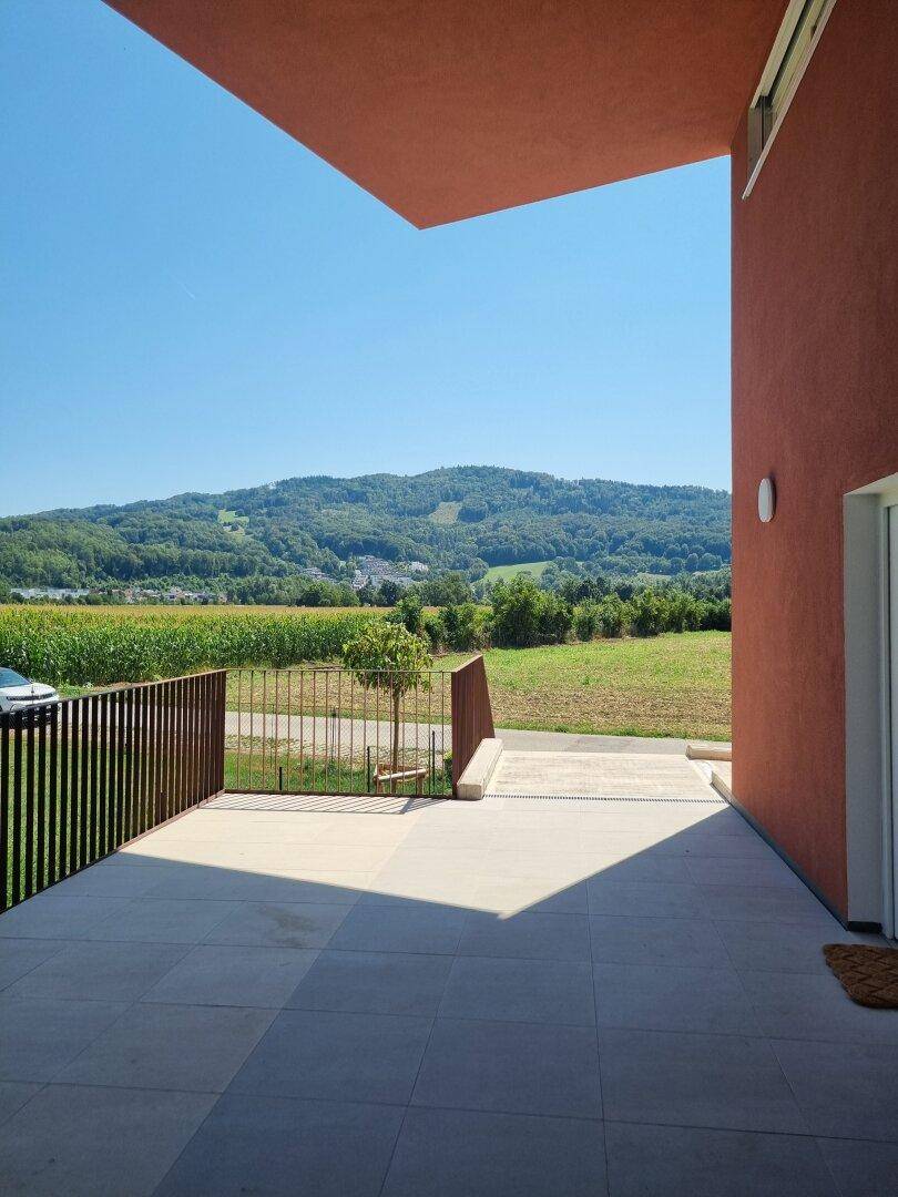 Geräumige Terrasse mit Fliesenboden und weitem Blick auf die umliegende Landschaft und Berge.
