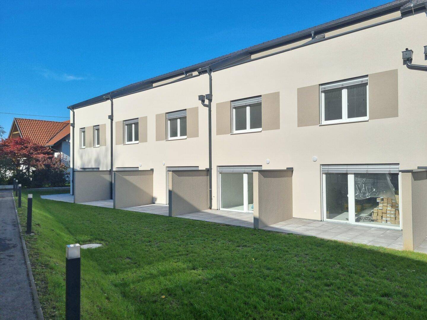 Reihe von modernen Neubau-Reihenhäusern mit kleinen Terrassen und Gärten.