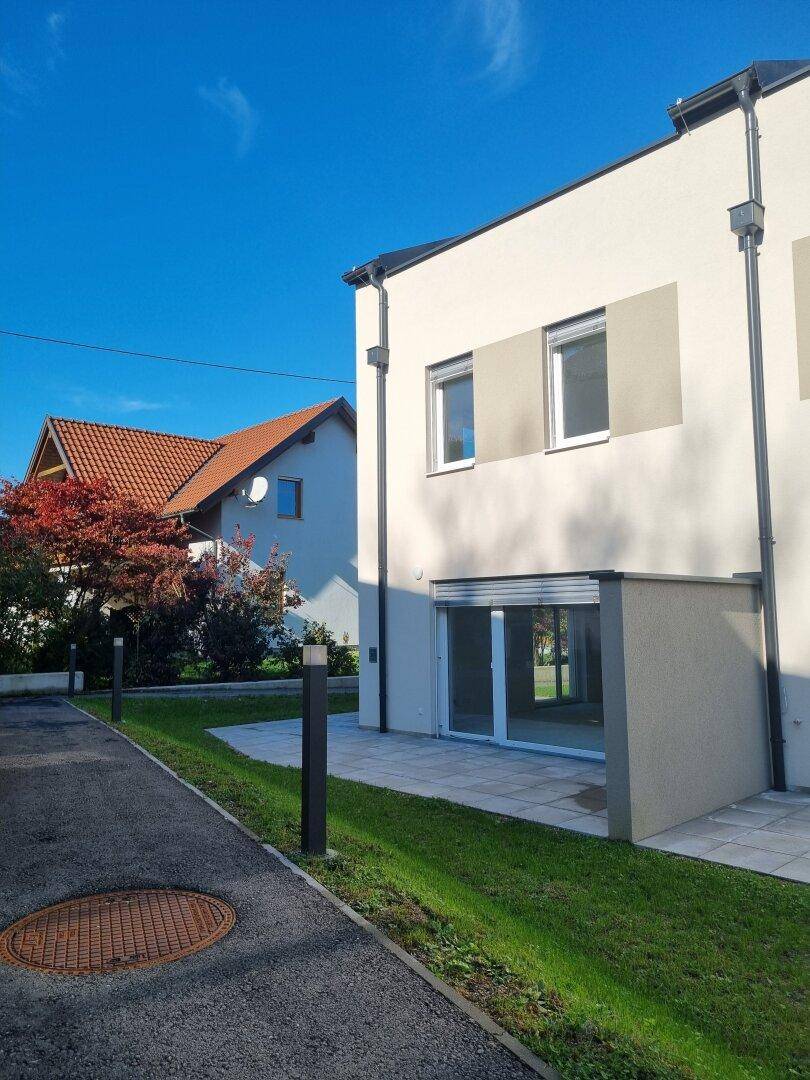 Seitenansicht eines modernen Neubau-Reihenhauses mit Terrasse und Gartenbereich.