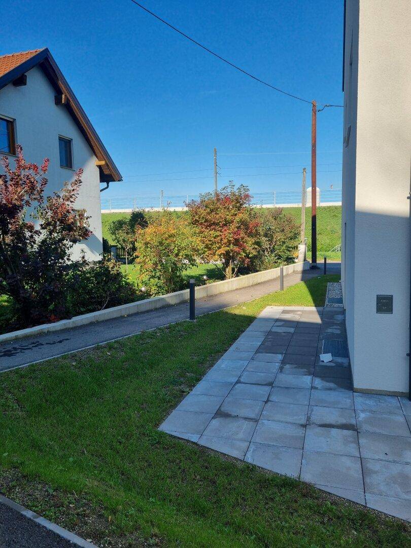 Außenbereich eines Reihenhauses mit gepflastertem Weg und Blick auf die Umgebung.