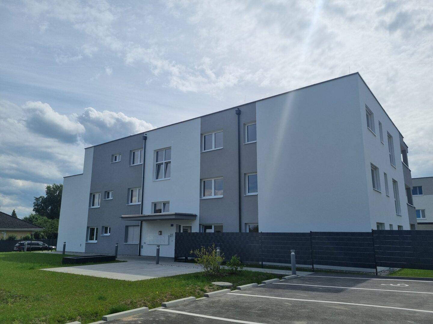 Neubau-Wohnkomplex mit moderner Architektur, Parkplätzen und Grünflächen.