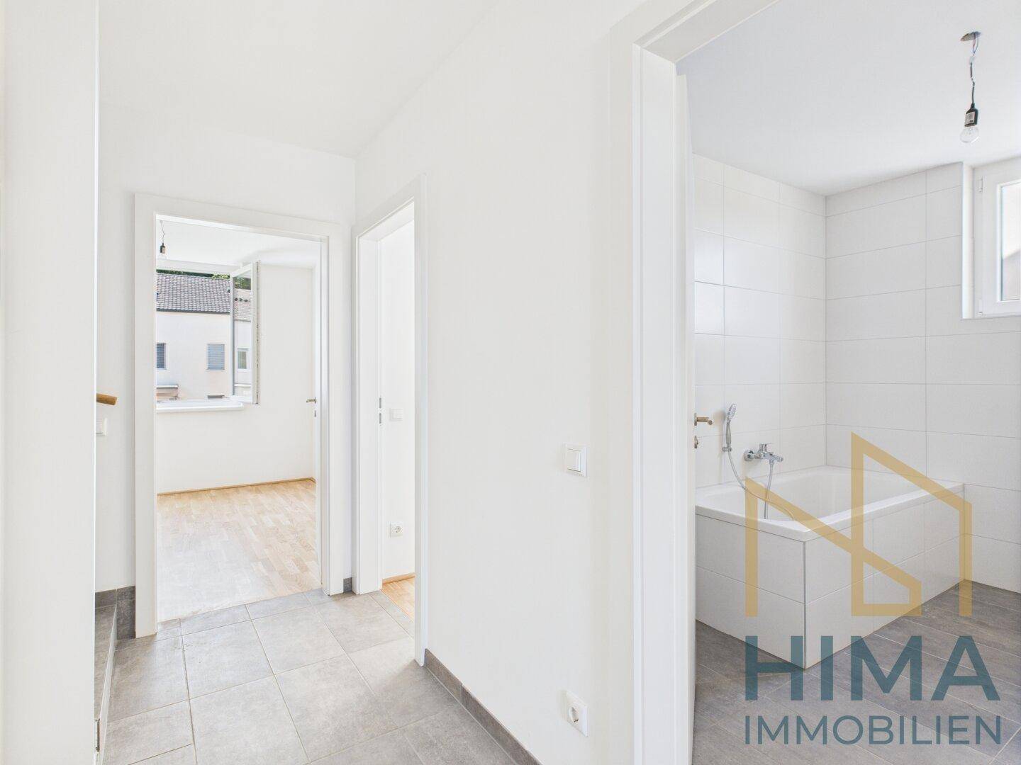Heller Flur mit Fliesenboden, der zu einem Badezimmer und weiteren Wohnräumen führt.