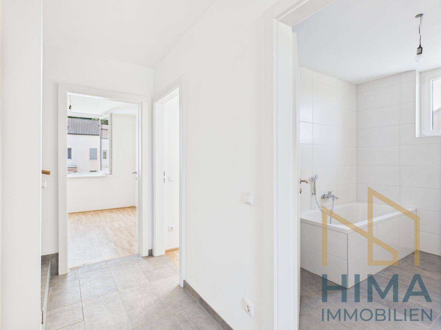 Heller Flur mit Fliesenboden, der zu weiteren Zimmern und einem Badezimmer führt.