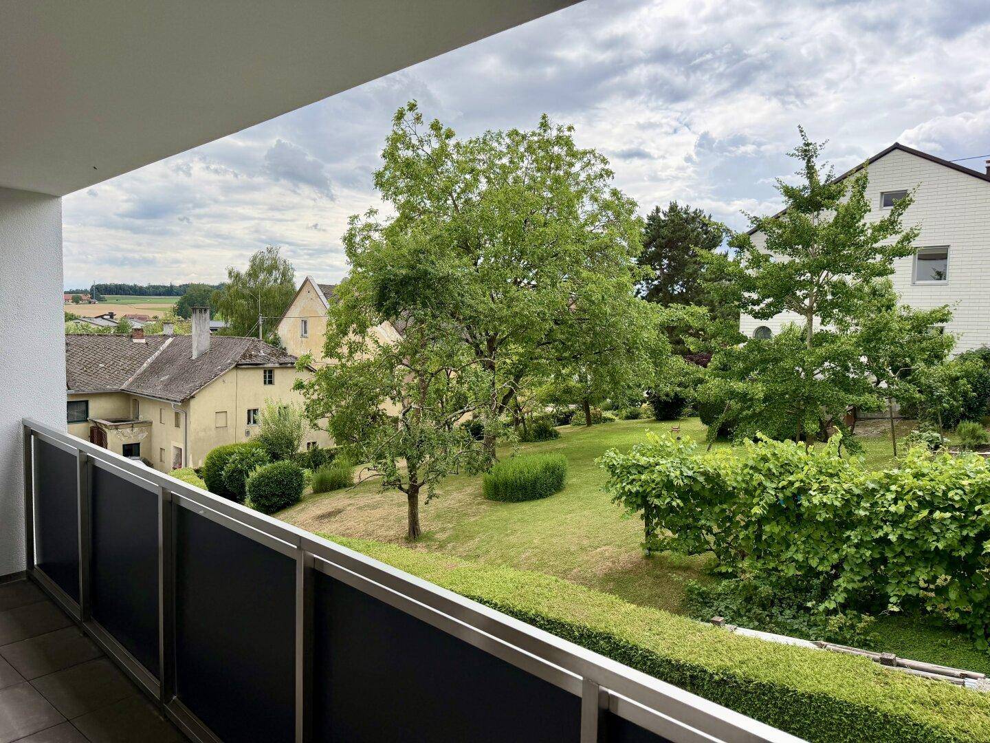 Balkon mit weitem Blick über eine grüne Landschaft mit Bäumen und ländlichen Häusern.