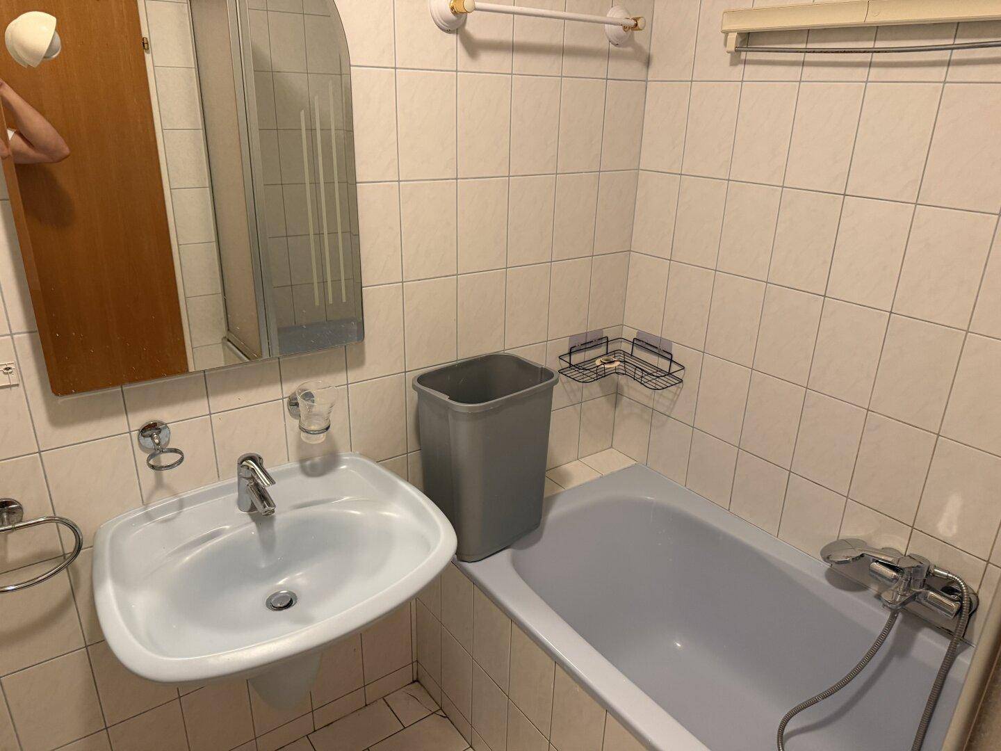 Badezimmer mit Waschbecken, Badewanne und weißen Fliesen, praktisch eingerichtet.