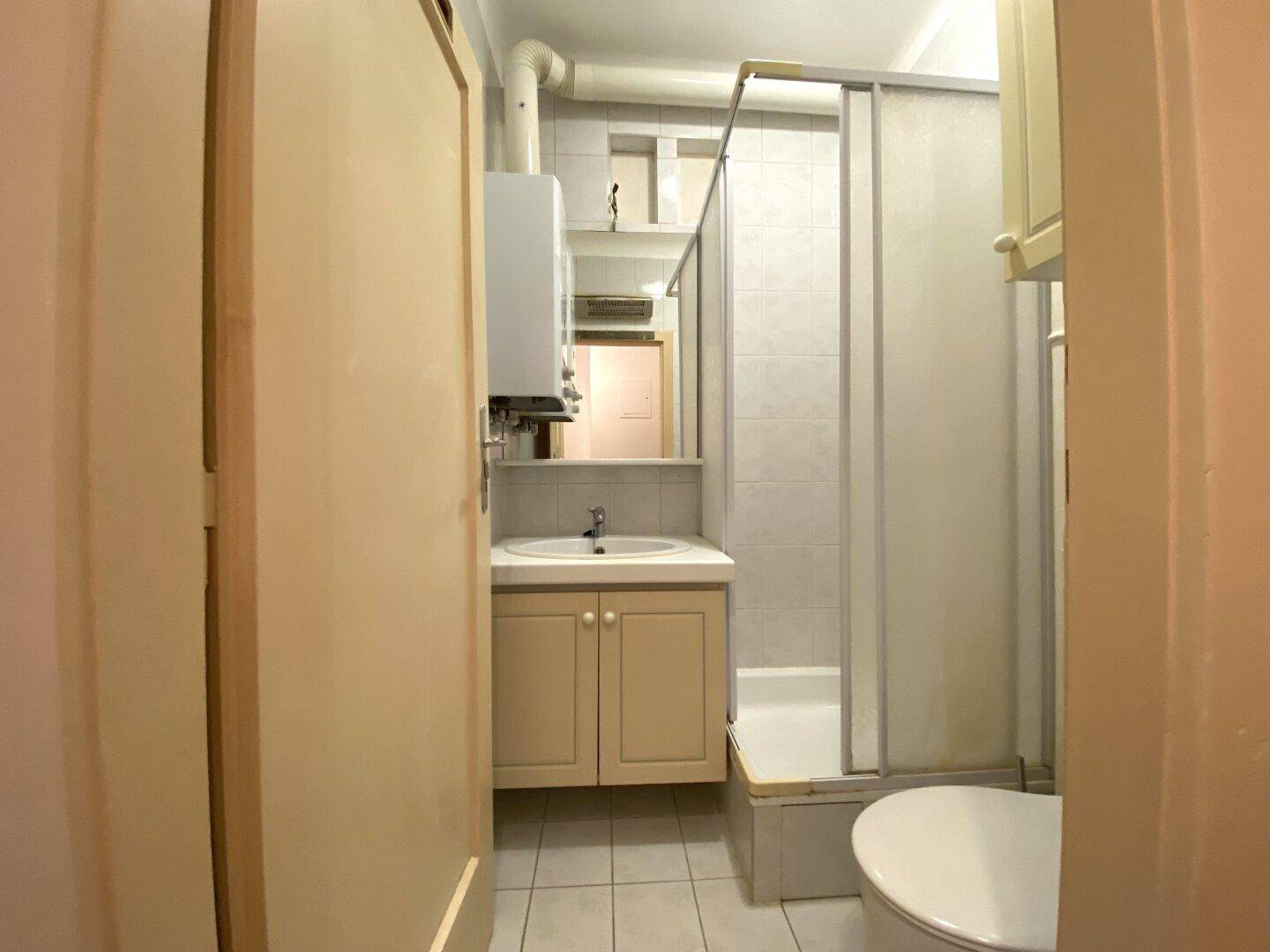 Kleines Badezimmer mit Dusche, Waschbecken und WC, ausgestattet mit Fliesenboden.