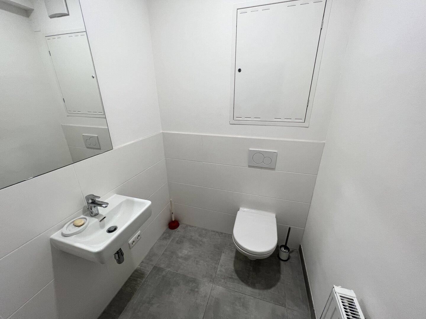 Funktionale Gästetoilette mit wandhängendem WC und kleinem Handwaschbecken.