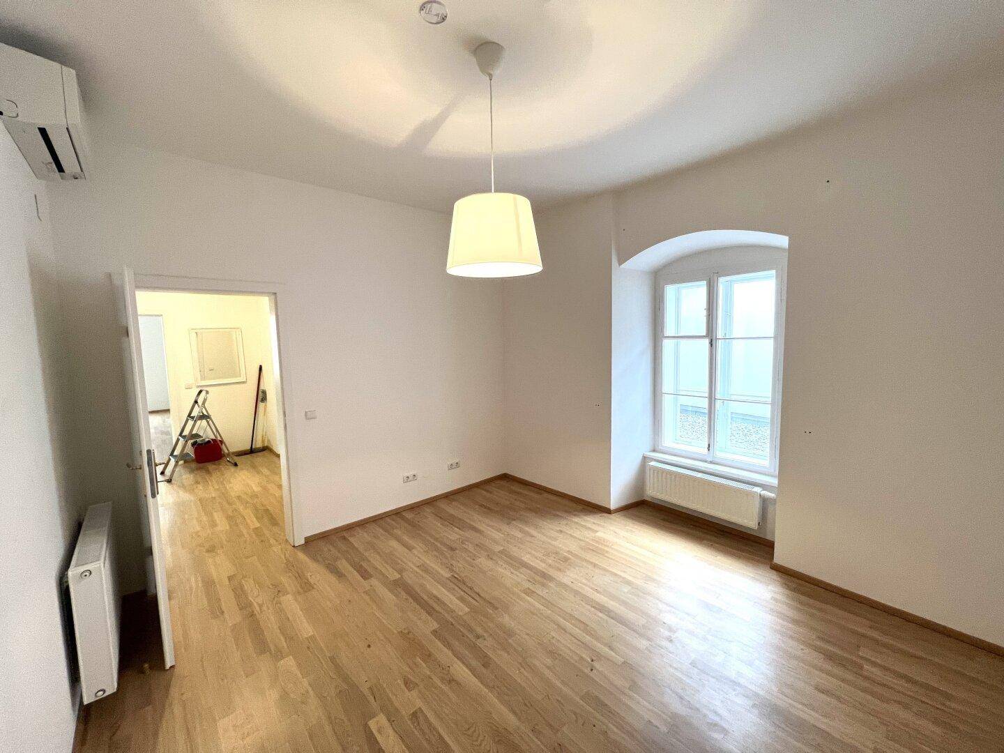 Geräumiges Zimmer mit Holzboden und Klimaanlage, ideal als Schlaf- oder Arbeitszimmer.