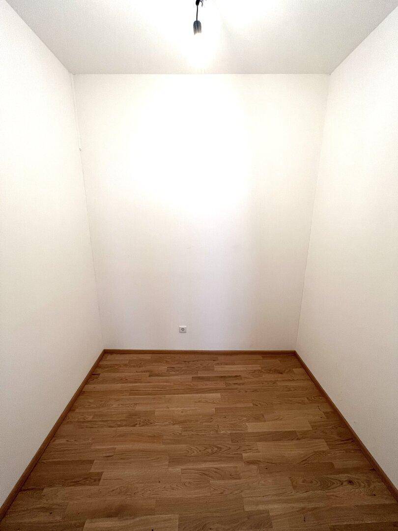 Kleiner, leerer Raum mit Holzboden, ideal als Abstellraum oder begehbarer Kleiderschrank.
