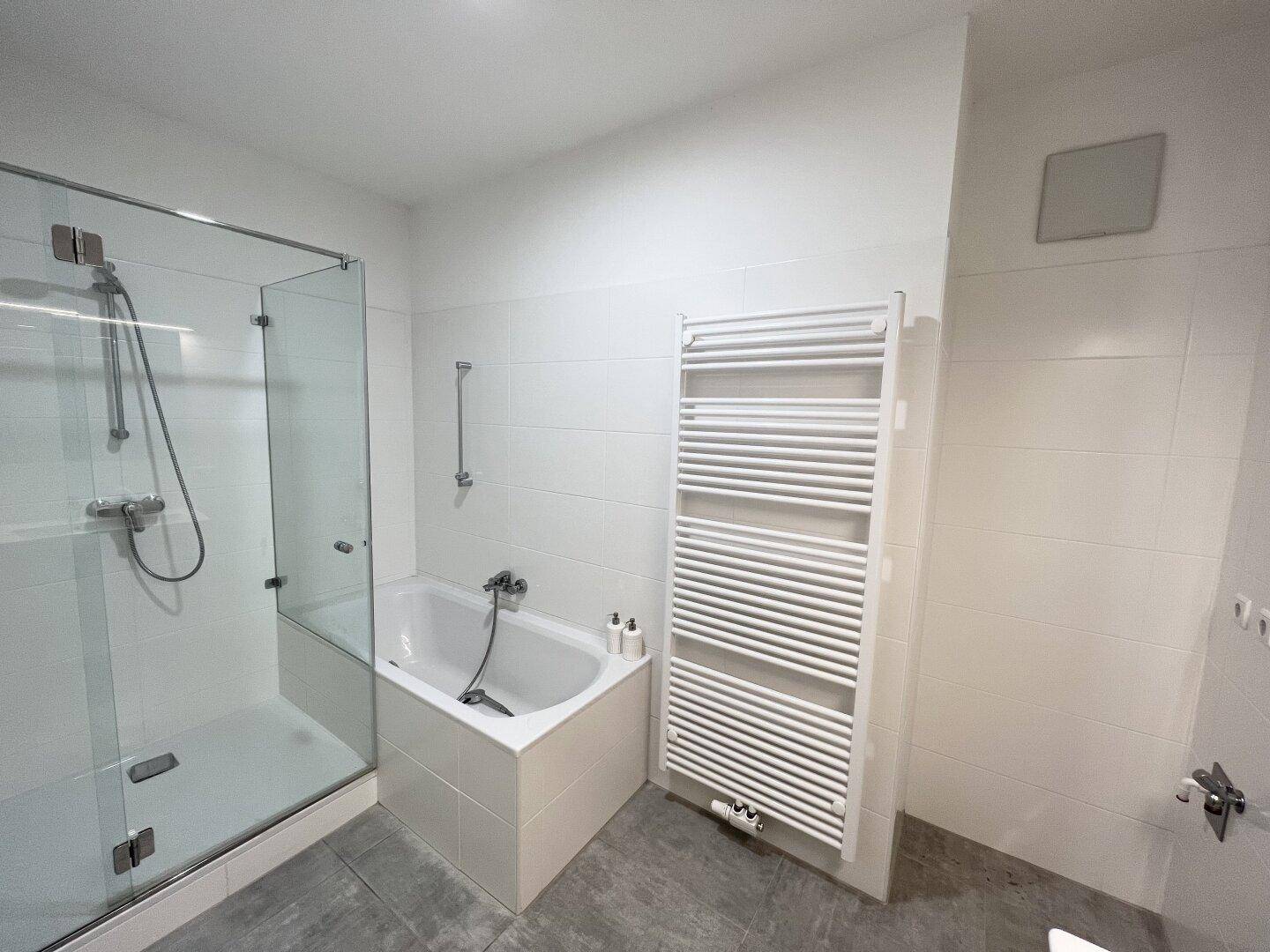 Helles Badezimmer mit Duschkabine, Badewanne und praktischem Handtuchheizkörper.